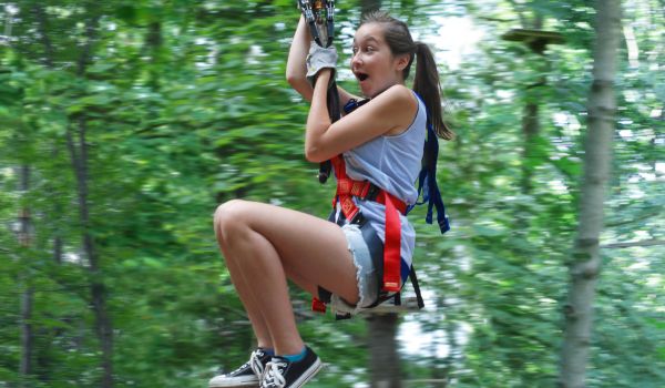 A girl looking excited as she zooms down a zipline at the Catamount Aerial Adventure Park