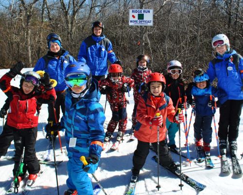 A large group of kids smiling with their ski instructors at Catamount Ski Resort