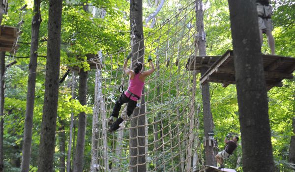 A woman on the rope net at the aerial adventure park at Catamount Resort