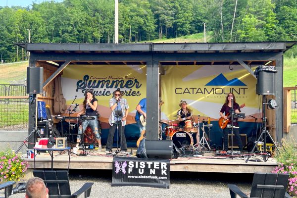 Two kids and a camp instructor cheering at the top of a zipline at Catamount Resort