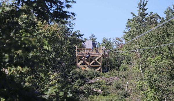 Looking back at a person just starting the zipline at Catamount Resort