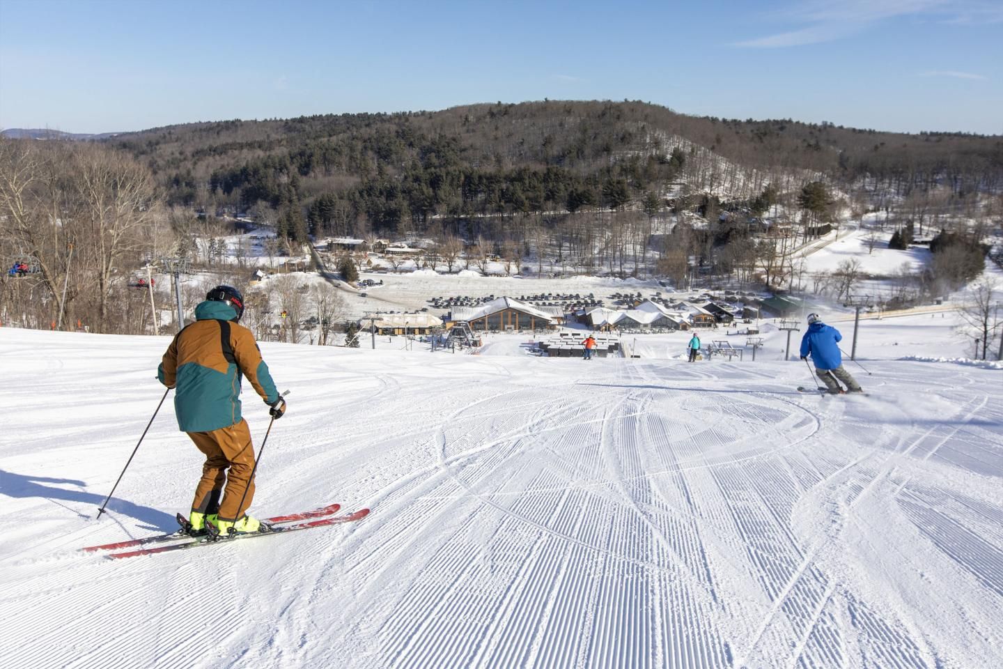 Two skiers carving nice turns on fresh groomed snow headed towards the lodge at Catamount Ski Resort