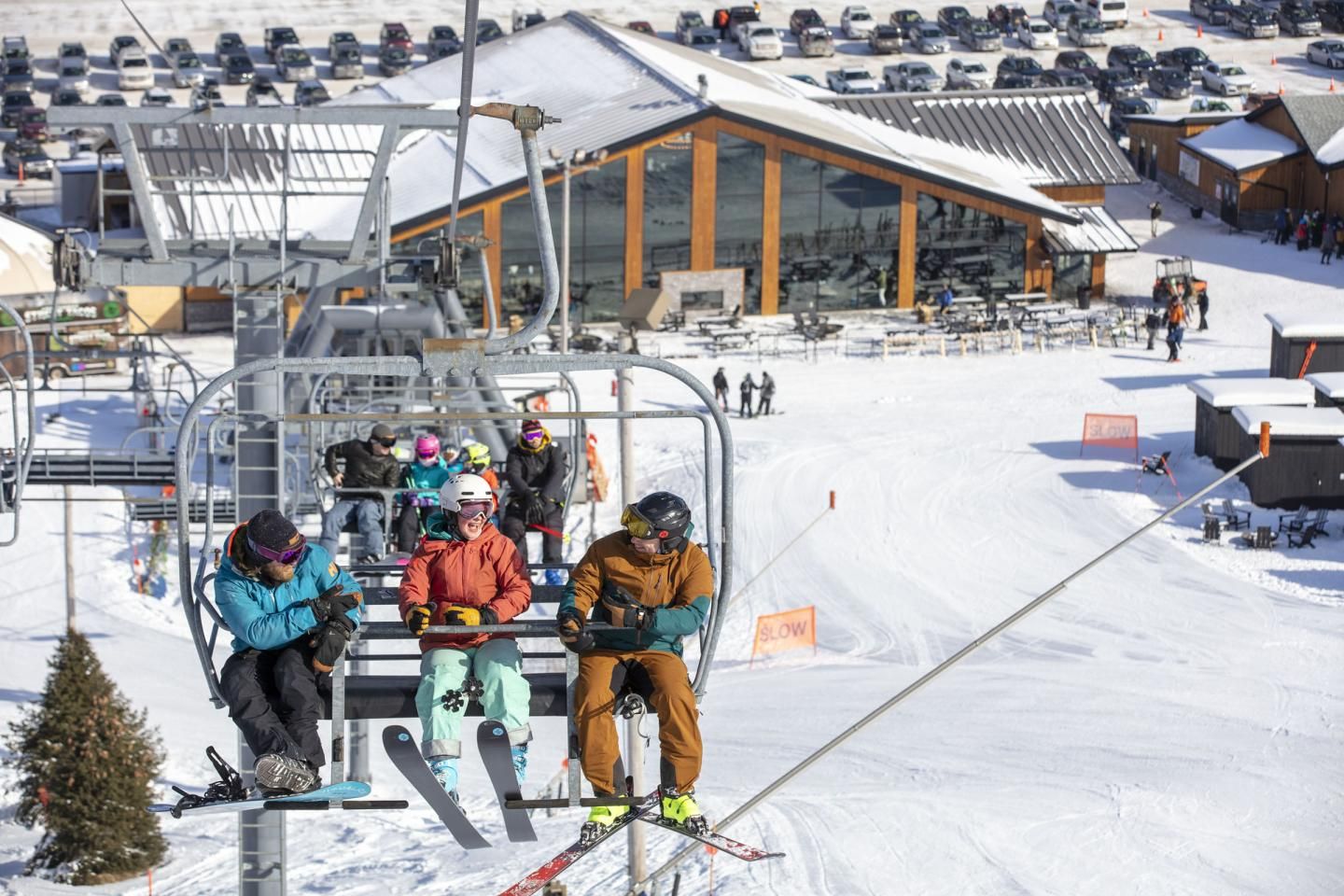 Three friends smiling on the chairlift above Catamount lodge