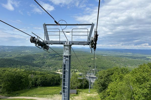 Two empty chairlifts in the Summer with a view of the valley below