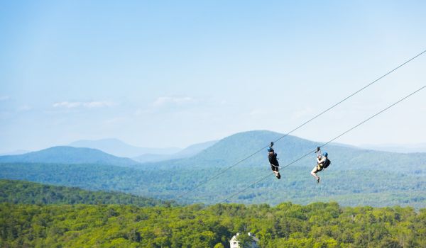 Two people high above the valley on the Catamount Zipline