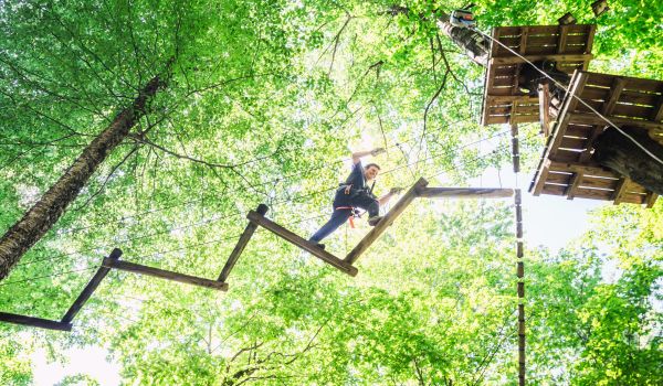 A smiling climber in the Aerial Adventure Park at Catamount