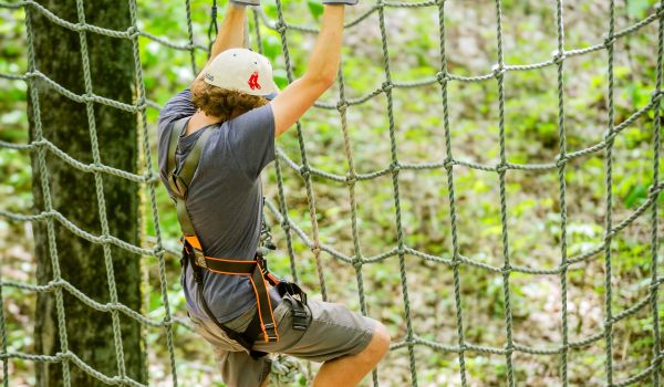 A man on the rope net at the aerial adventure park at Catamount Resort