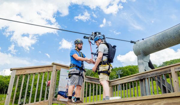A zip guide loading a guest onto the demo zipline at Catamount Mountain Resort
