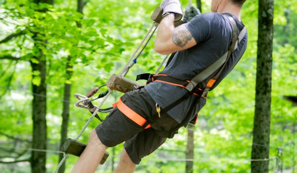 A man swinging on a ladder swing in the aerial adventure park at Catamount Resort