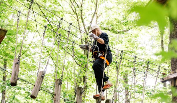 A girl climbing on a wooden bridge at the aerial adventure park at Catamount Resort