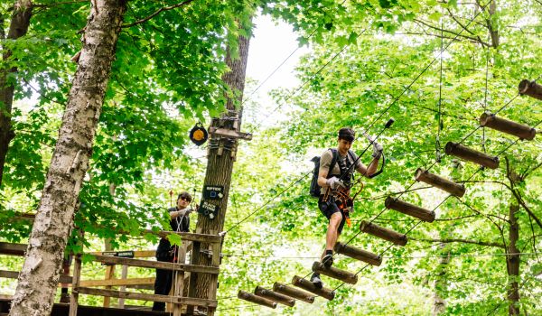 A man walking across a bridge in the Aerial Adventure Park
