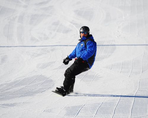 A lone snowboard instructor carving a turn on freshly groomed snow at Catamount Ski Resort