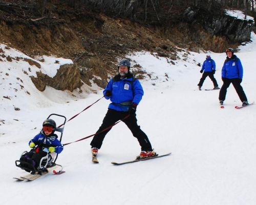 Ski Instructors using a ski chair and leash in the Stride Adaptive Program