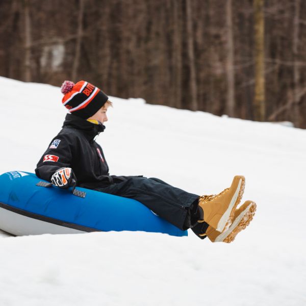 kid on snow tube sliding down hill